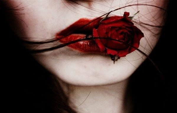 Röda läppar och ros på kvinna som vill finna svar