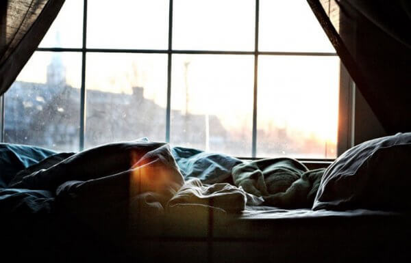 Person i sängen som har svårt att kliva upp på morgonen