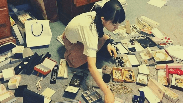 Marie Kondo sitter på golvet och organiserar sina smycken metodiskt.