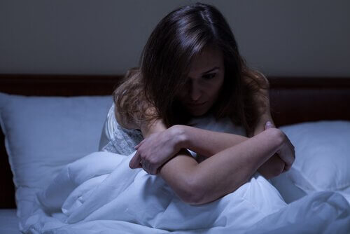 Kvinna i sängen som känner att natten ger bränsle till vår oro