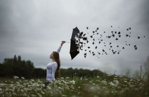 Kvinna på äng med söndervittrande paraply