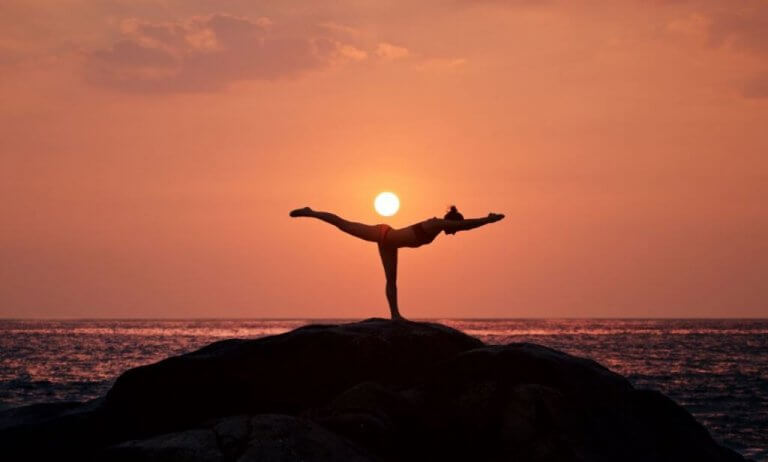 Kvinna som utför yoga vid havet.
