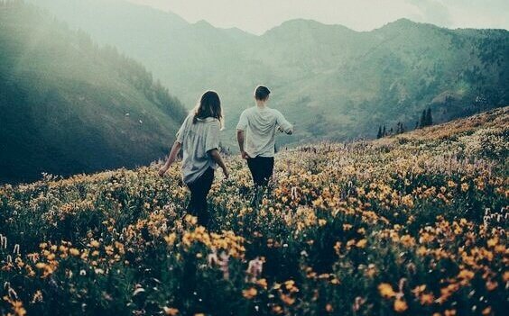 Par som går igenom fält med blommor.