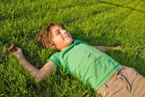 Pojke som ligger i gräset.