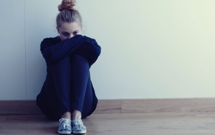 Tjej sitter på golvet i djupa tankar