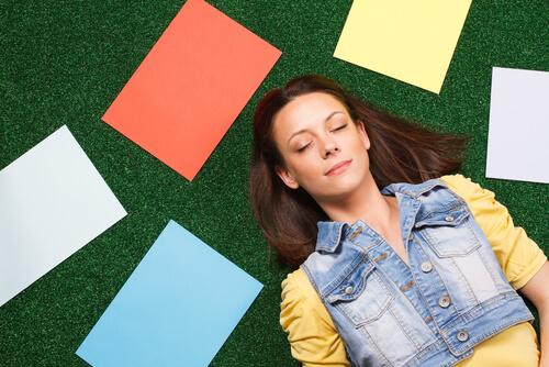 Kvinna som ligger ner bredvid pappersark i olika färger.