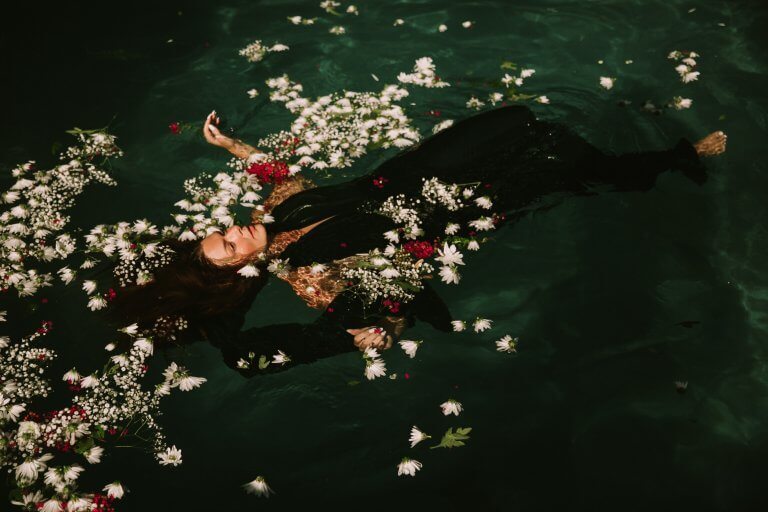 Kvinna som flyter bland blommor.
