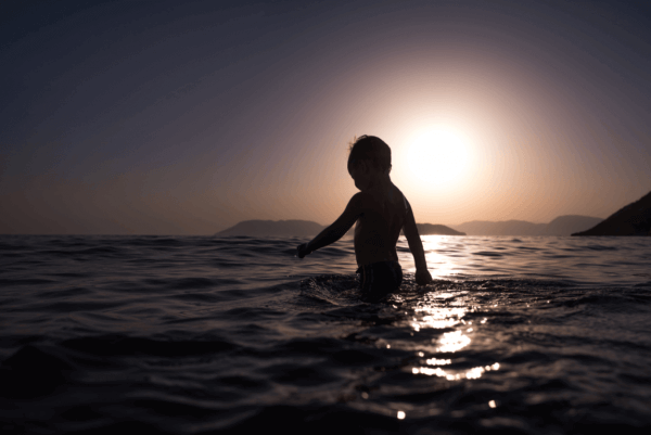En liten pojke som badar i havet