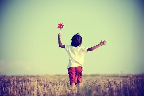 Pojke med vindsnurra leker självständigt på fält