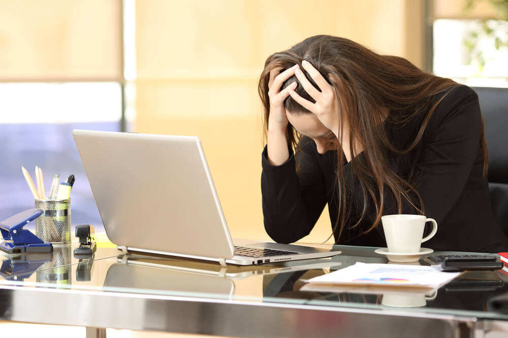 Kvinna som ser trött ut framför sin laptop.