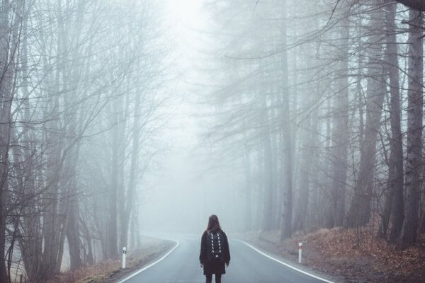 Ensam kvinna på en väg i skogen