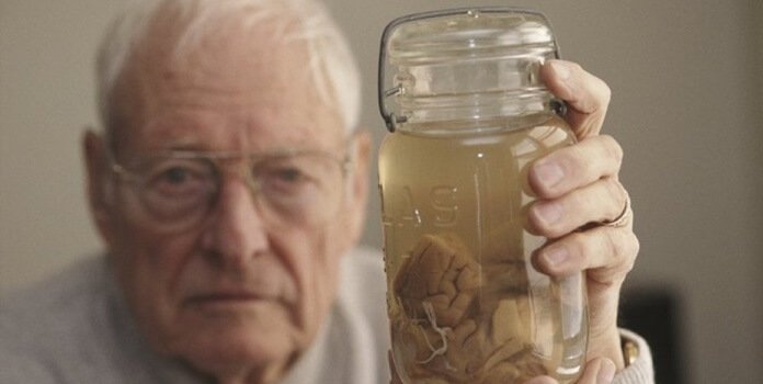 Man som håller upp glasburk med hjärna.