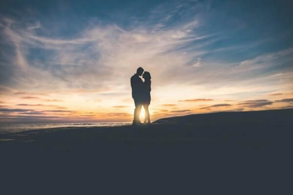 Par håller om varandra vid solnedgång