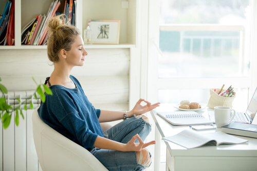Kvinna mediterar inomhus vid skrivbord