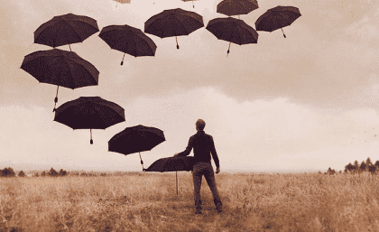 Man på ett fält med massor av paraplyer i luften 
