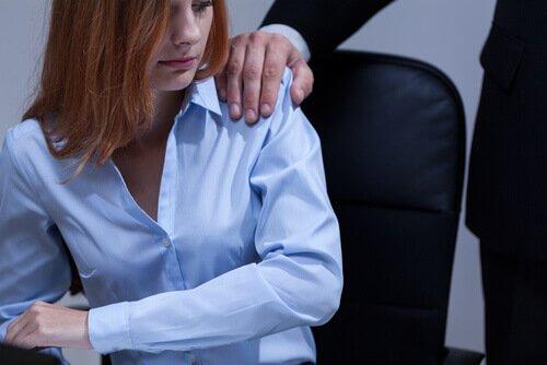 En kvinna på ett kontor med en mans hand på axeln