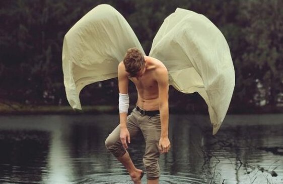 Man med vingar badar i sjö