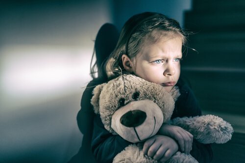 Ledsen flicka som kramar sin nallebjörn