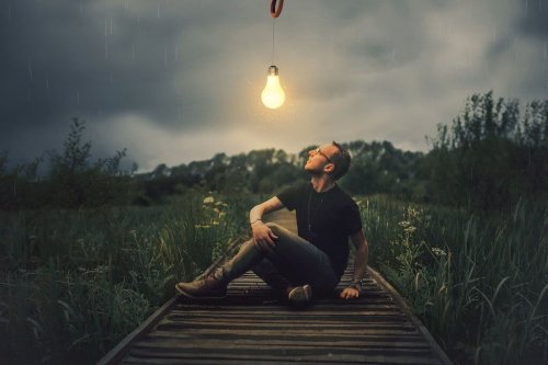 Man som sitter under tänd glödlampa