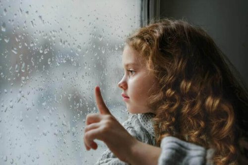 Flicka som ser ut genom fönster i regn