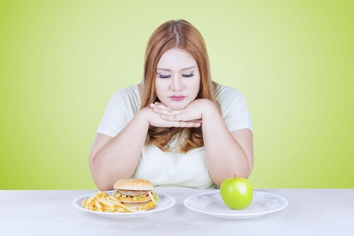 Kvinna som väljer mellan skräpmat och äpple.