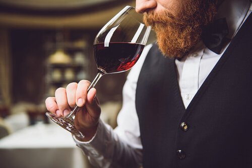 Man med skägg som luktar på vin.