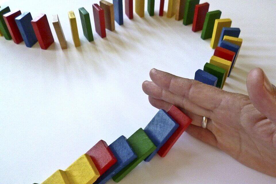 Hand som stoppar dominobrickor