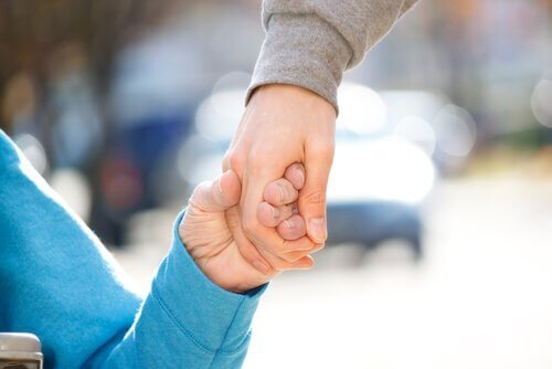 barn och vuxen som håller hand