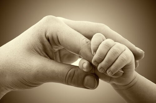 Bebishand som håller en vuxen hand.
