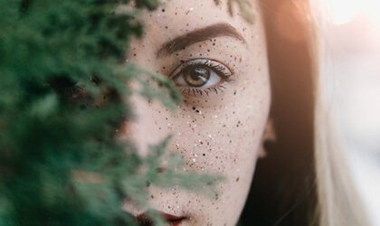 Kvinna bakom ett träd.