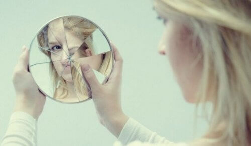 En kvinna tittar på sig själv i en trasig spegel.