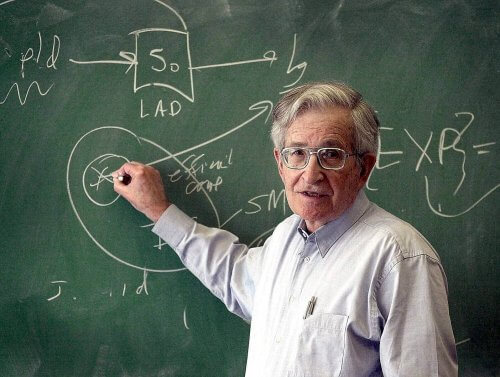 Noam Chomsky står och skriver vid en griffeltavla.