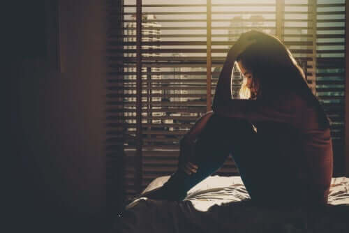 Kvinna som sitter på sängen.