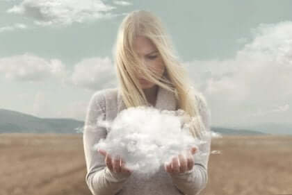 Kvinna som står på en åker med ett moln i sina händer