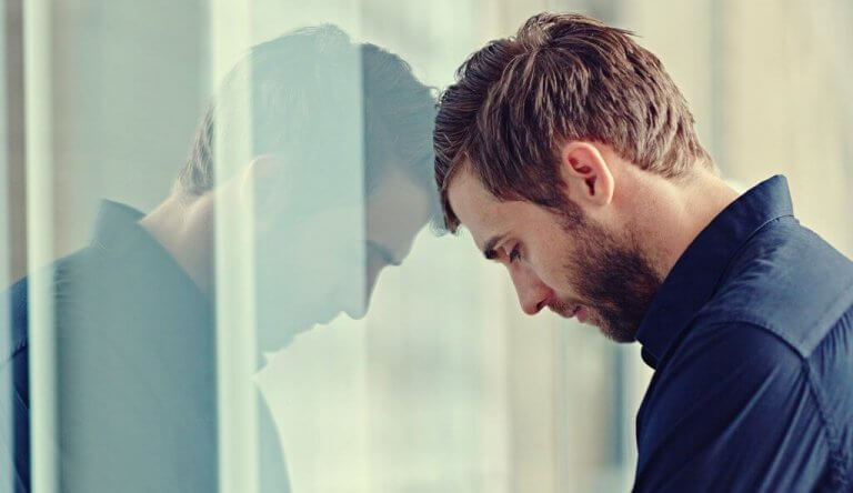 Man som står med huvudet mot en ruta.