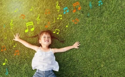 En liten flicka som ligger på gräset och lyssnar på musik.