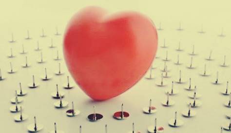 En hjärtformad ballong som är omgiven av häftstift.