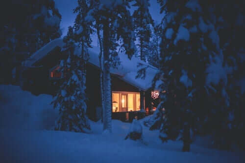 Hus med snö i skogen.