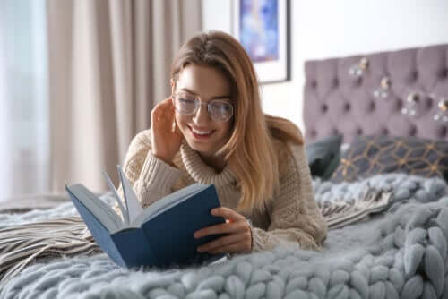En kvinna som lever som särbo från sin partner som ligger hemma hos sig själv och läser en bok.