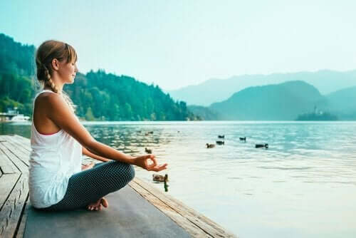 Kvinna som mediterar vid sjö.