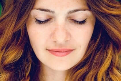 En kvinna som ler med slutna ögon.