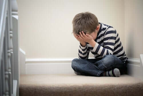 En pojke med skolfobi som sitter på trappan i sitt hem och gråter.