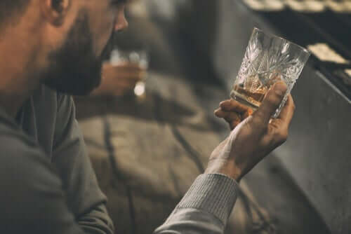 En man tittar på sin drink medan han överväger behandling för alkoholism.