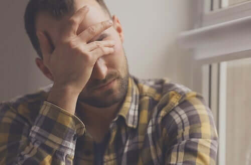 En man som vilar ansiktet i handen av stress på grund av att han har ett öppet sår.
