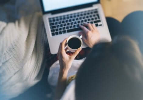 En kvinna som dricker kaffe och arbetar på sin dator