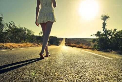 En kvinna följer en lång, enslig väg barforta mot gryningens solsken