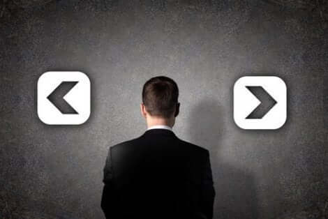 En man som tittar på en vägg med två motsatta pilar