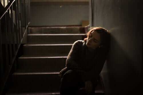 En ledsen kvinna lutad mot väggen i en trappuppgång