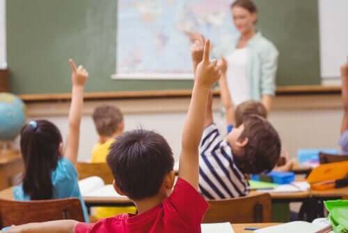 Barn i skolan räcker upp handen