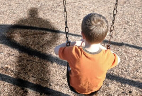 Ledsen pojke som sitter på gungan på grund av emotionell försummelse av barn hemma